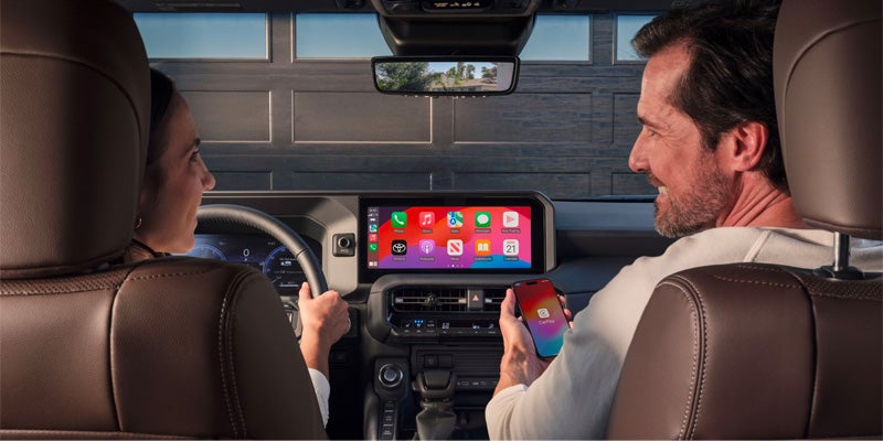 Two people enjoying the infotainment system of safety features in the 2024 Toyota Land Cruiser in Akron, OH